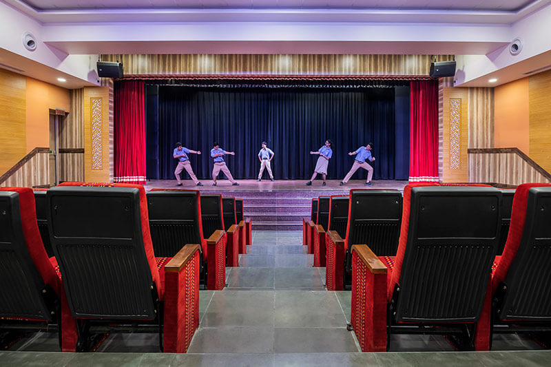 Students performing on stage in the auditorium of BLS World School Greater Noida West